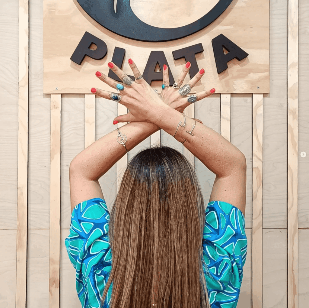 Mujer vestida de azul de espaldas con varios anillos y pulseras